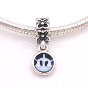 May include: A silver charm featuring a Libra scale design. The charm has a round, black and white pendant with the Libra symbol, and a decorative top with floral cutouts. The charm is attached to a silver bracelet.