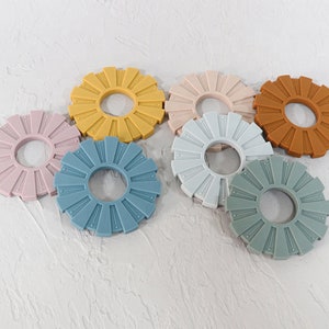 May include: Six silicone coasters in various colors, including light blue, dark blue, light green, brown, pink, and beige. Each coaster has a circular shape with a raised center ring and a textured outer edge.