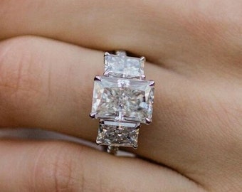 May include: A silver ring with three large, rectangular, clear gemstones set in a row.