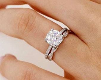 May include: A diamond engagement ring set with a round center stone and a matching band. The ring is set in white gold and features a pave setting.