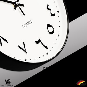 Pu&ograve; includere: Un orologio bianco e nero con numeri arabi. Il quadrante dell'orologio &egrave; bianco con numeri e lancette neri. L'orologio &egrave; etichettato "QUARTZ" e ha un bordo nero.