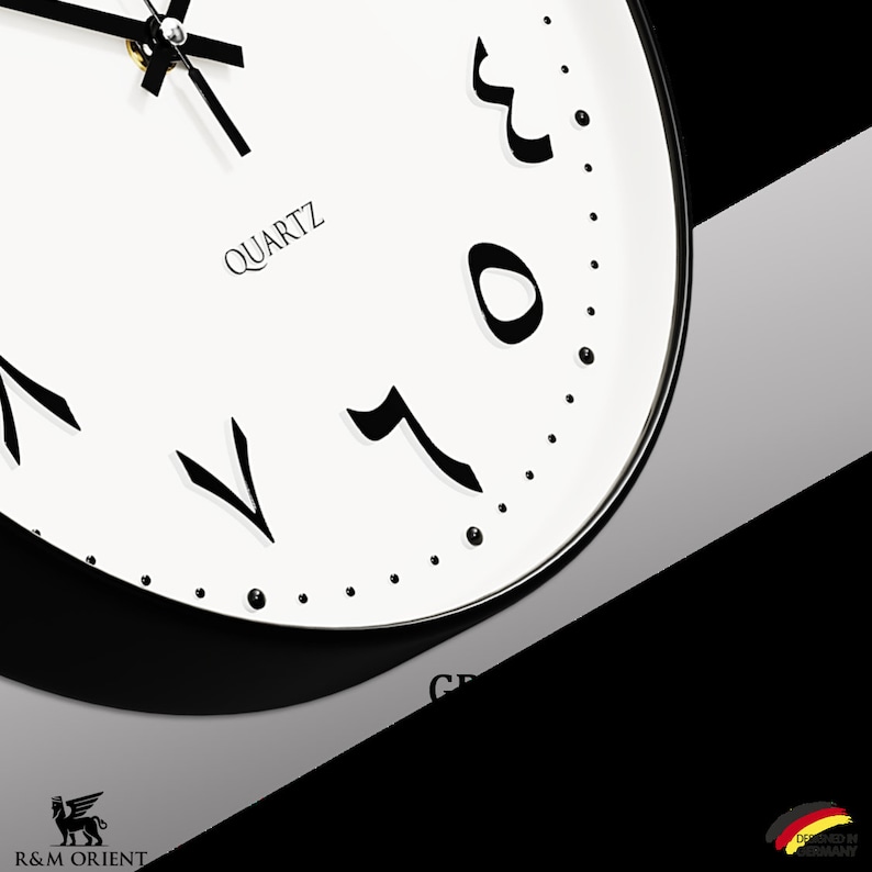 Pu&ograve; includere: Un orologio bianco e nero con numeri arabi. Il quadrante dell'orologio &egrave; bianco con numeri e lancette neri. L'orologio &egrave; etichettato "QUARTZ" e ha un bordo nero.