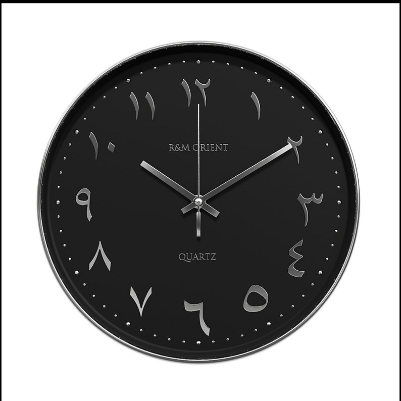 Pu&ograve; includere: Un orologio da parete nero con numeri arabi e lancette argentate. Il quadrante dell'orologio recita "R&M Orient Quartz".