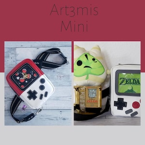 May include: Two mini game console-shaped bags. One is red and white with a black strap, featuring a Pokemon design. The other is white with a grey border, displaying a Zelda game screen. The image also includes a gold-coloured Zelda game console.