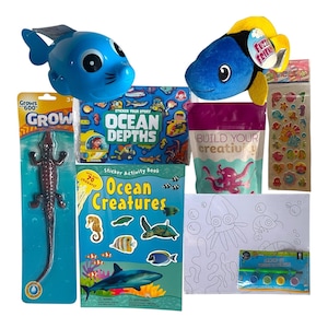 Pode incluir: Uma coleção de brinquedos e materiais de artesanato infantis com tema oceânico. Inclui um brinquedo de foca azul, um peixe de pelúcia azul e amarelo, livros de adesivos, um conjunto de pintura e um brinquedo de jacaré de borracha.