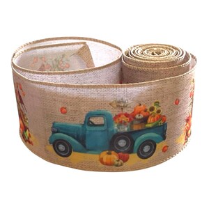 May include: A roll of tan burlap ribbon featuring a repeating print of a teal vintage pickup truck carrying orange pumpkins and sunflowers. The ribbon has a textured, woven appearance with finished edges and a seasonal autumn theme.