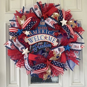 Pu&ograve; includere: Una ghirlanda patriottica rosso, bianco e blu con un cartello che recita "God Bless America Welcome Let Freedom Ring". La ghirlanda &egrave; decorata con stelle, nastri e rete.
