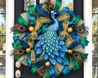 Peut inclure: Une couronne décorative présentant une figure centrale de paon bleu et vert entourée de rubans en maille dorée métallique, de tissu vert scintillant et de plumes de paon naturelles. Le design inclut plusieurs ornements sphériques dorés.