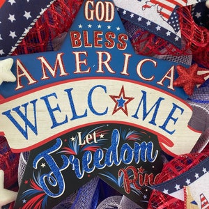 Pu&ograve; includere: Un cartello a forma di stella blu e rosso con il testo "God Bless America" e "Welcome" su di esso. Il cartello ha anche il testo "Let Freedom Ring" su di esso. Il cartello &egrave; decorato con glitter e stelle.