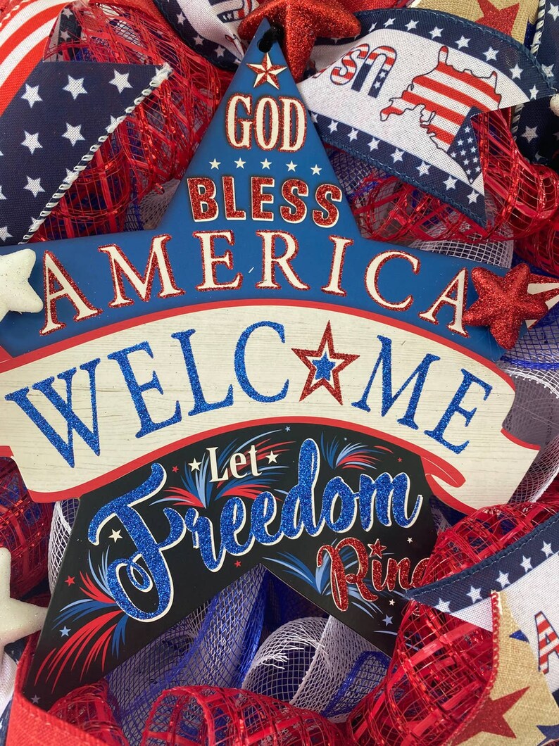 Pu&ograve; includere: Un cartello a forma di stella blu e rosso con il testo "God Bless America" e "Welcome" su di esso. Il cartello ha anche il testo "Let Freedom Ring" su di esso. Il cartello &egrave; decorato con glitter e stelle.
