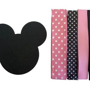 May include: A black Mickey Mouse head-shaped item is next to four headbands. The headbands are pink with white polka dots, black with white polka dots, solid pink, and solid black.
