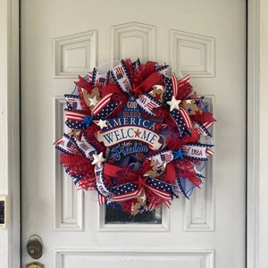 Pu&ograve; includere: Una ghirlanda patriottica rosso, bianco e blu con un cartello che recita "God Bless America Welcome Let Freedom Ring".
