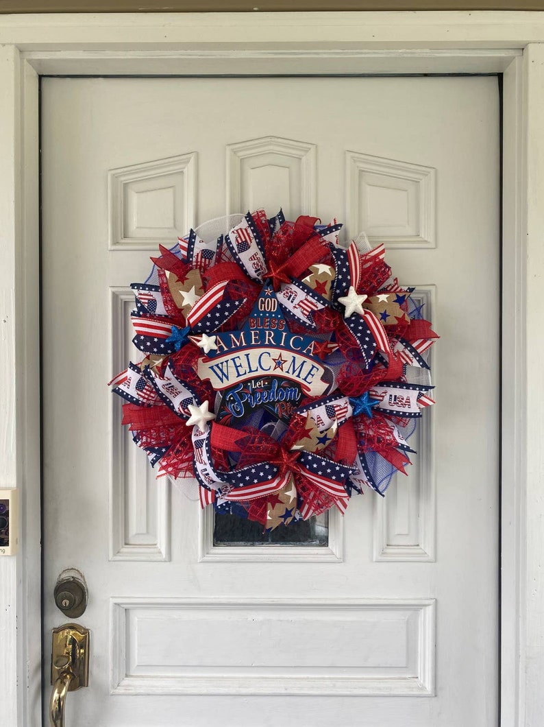 Pu&ograve; includere: Una ghirlanda patriottica rosso, bianco e blu con un cartello che recita "God Bless America Welcome Let Freedom Ring".