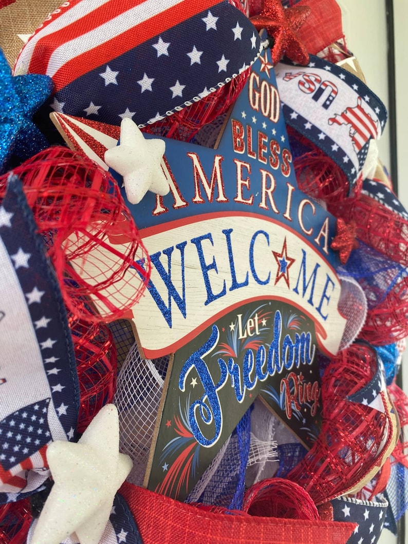 Pu&ograve; includere: Una ghirlanda patriottica rosso, bianco e blu per la porta con un cartello a forma di stella che recita "God Bless America Welcome Let Freedom Ring".