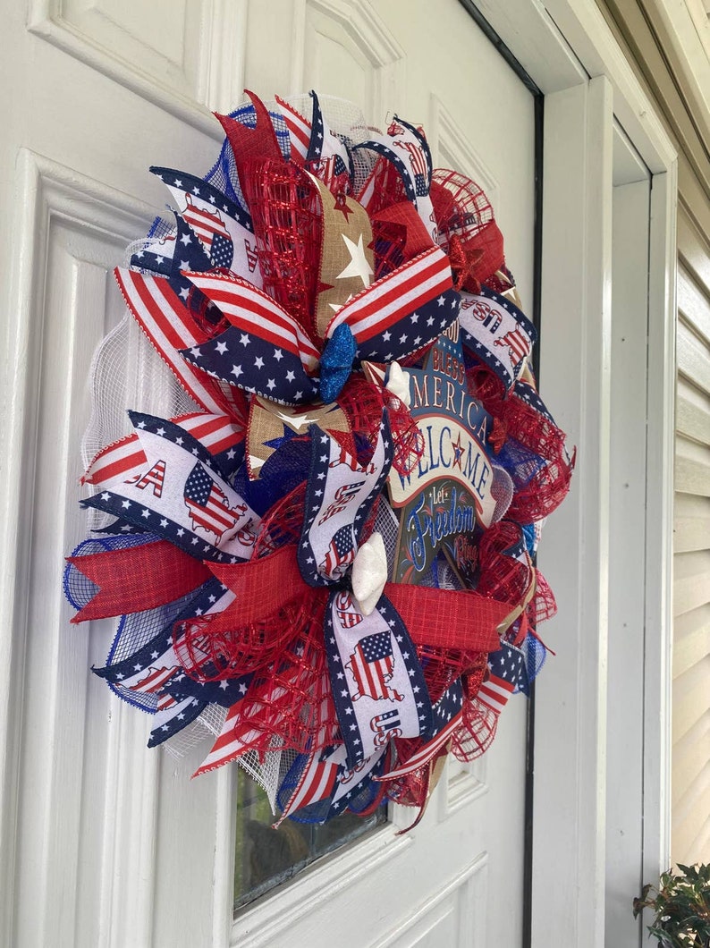 Pu&ograve; includere: Una ghirlanda patriottica rosso, bianco e blu con un cartello che dice "God Bless America Welcome Let Freedom Ring".