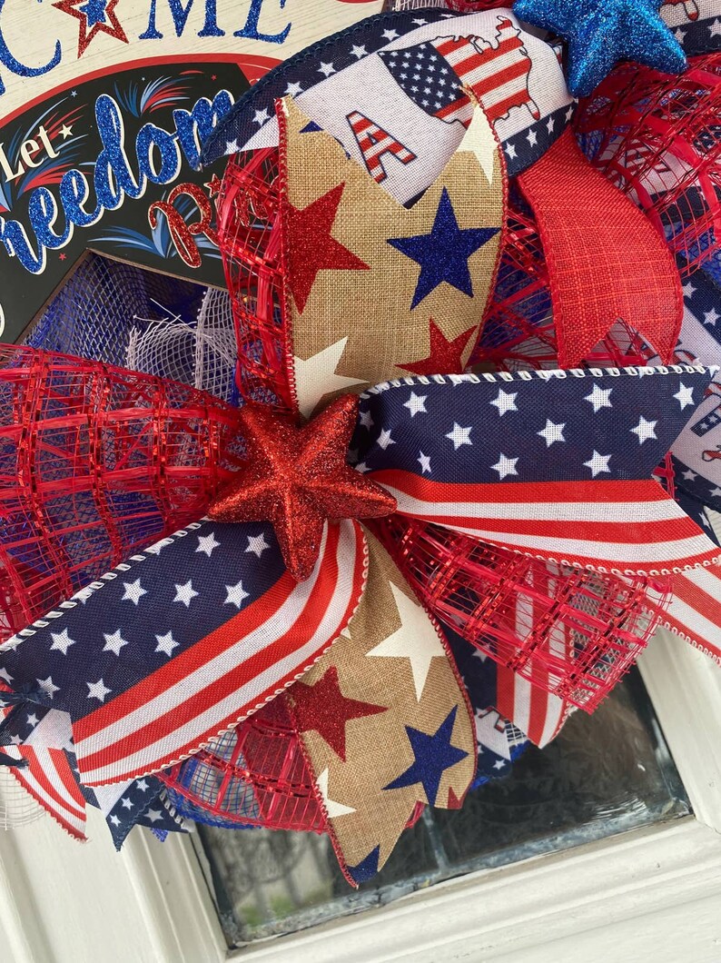 Pu&ograve; includere: Una ghirlanda patriottica rosso, bianco e blu con un fiocco di juta, stelle e un cartello che dice "Let Freedom Ring".