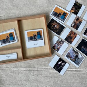 May include: A wooden tray with three compartments, containing a set of flashcards with images of people dancing the tango. The cards are labelled with the word "tango".