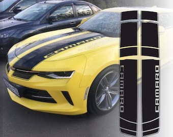 May include: Black and yellow car hood stripes with the word "CAMARO" printed in white. The stripes are designed to be applied to a car hood.
