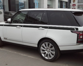 May include: A white Range Rover SUV with black accents and a black stripe along the side. The vehicle is parked in a parking lot.