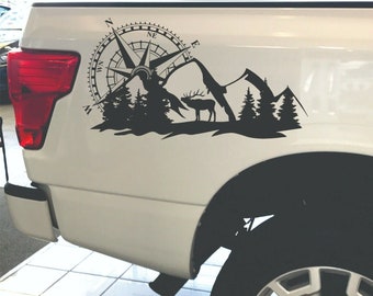 May include: Black and white decal of a compass, mountains, and an elk on the side of a white pickup truck.