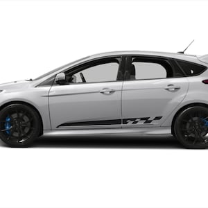 May include: A white Ford Focus RS hatchback with black racing stripes on the side. The car has black wheels and a black rear spoiler.