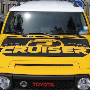 May include: A yellow Toyota FJ Cruiser with a black hood decal that says "FJ Cruiser" with a silhouette of the vehicle and mountains in the background.