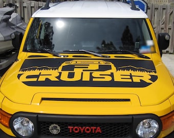 May include: A yellow Toyota FJ Cruiser with a black hood decal that says "FJ Cruiser" with a silhouette of the vehicle and mountains in the background.