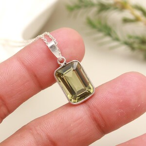 May include: A silver chain necklace with a pendant featuring a large, rectangular, light green gemstone.