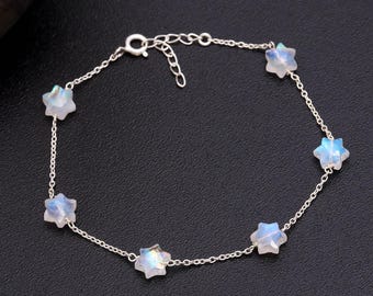 May include: A delicate silver bracelet featuring six star-shaped gemstones. The gemstones have a pearlescent, iridescent quality, with hints of blue and white. The bracelet is connected by a fine silver chain and has an adjustable clasp.