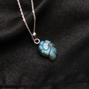 May include: A silver chain necklace with a blue labradorite pendant carved in the shape of a leaf.