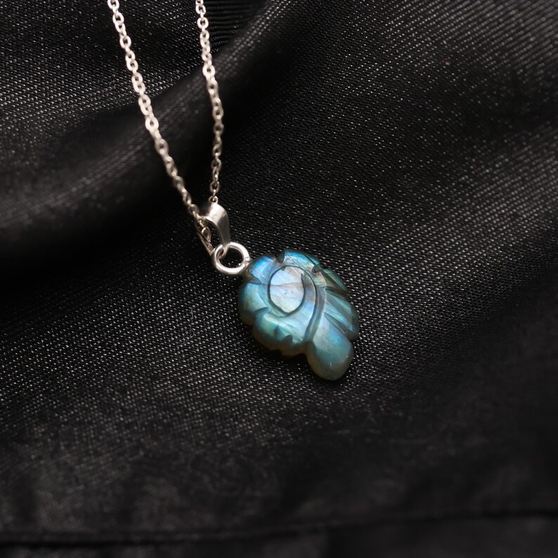 May include: A silver chain necklace with a blue labradorite pendant carved in the shape of a leaf.