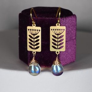 May include: Gold earrings with a floral design and iridescent blue teardrop-shaped stones.