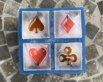 May include: A blue ice cube tray with four compartments, each containing a frozen playing card symbol. The symbols are a spade, a diamond, a heart, and a club. The tray is labeled "GATSBY CUSTOMS".
