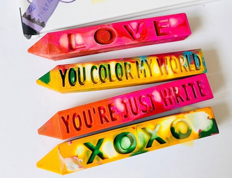 Pu&ograve; includere: Quattro pastelli colorati con messaggi diversi: "LOVE", "YOU COLOR MY WORLD", "YOU'RE JUST WRITE" e "XOXO".