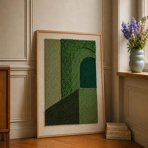 May include: A rectangular wall art piece featuring a tufted textile design in various shades of green. The artwork displays geometric shapes, including a dark green archway and textured panels, all encased within a light-coloured wooden frame.