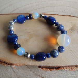 Könnte beinhalten: Ein blaues und weißes Perlenarmband mit silbernen Akzenten. Das Armband besteht aus blauen Lapislazuli- und weißen Opalperlen.