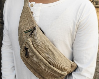 May include: A tan hemp fanny pack with two zippered compartments and a green "TRESCAPE" logo. The fanny pack is worn by a person wearing a white long-sleeved shirt.