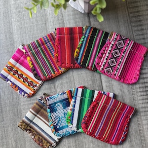 May include: A collection of colorful, woven fabric pouches with various striped and patterned designs. The pouches feature a variety of colors, including pink, red, blue, green, and brown. Each pouch has a unique pattern and is trimmed with a decorative stitch.