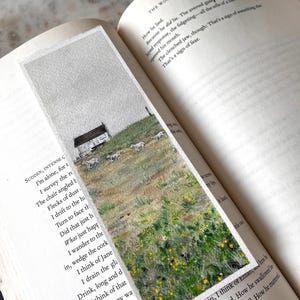 May include: A hand-painted bookmark depicting a rural scene with a white cottage, sheep, and wildflowers under a cloudy sky. The bookmark is set within an open book. A unique gift for book lovers. The bookmark is approximately 15 cm in length.