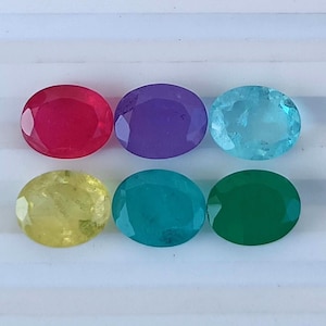 May include: Six oval-shaped gemstones in various colors: red, purple, blue, yellow, green, and dark green.
