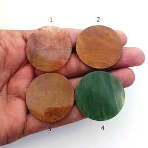 Peut inclure: Quatre pierres rondes, lisses et polies de différentes couleurs : rose clair avec du brun, brun, brun avec de l’orange et vert. Les pierres sont numérotées de 1 à 4.