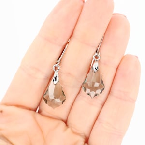 May include: A pair of silver dangle earrings with teardrop-shaped, faceted, smoky gray crystals.