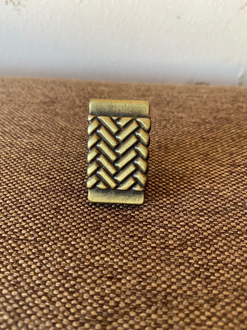 K&ouml;nnte beinhalten: Ein goldfarbener Metall-Schrankknauf mit gewebtem Design.