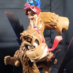 Könnte beinhalten: Detaillierte Donkey Kong-Statue mit einer Frau auf seinem Rücken. Die Statue ist braun und beige, mit einer roten Krawatte und blauen Akzenten. Der Sockel ist grau mit den Worten "DONKEY KONG" in Rot und Gelb.
