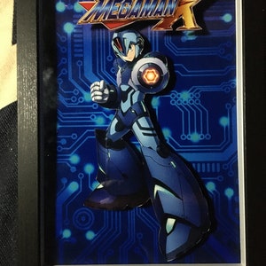 Könnte beinhalten: Eine gerahmte 3D-Illustration von Mega Man X, einem blauen Robotercharakter aus der Videospielserie, der auf einem blauen Schaltkreis-Hintergrund steht. Der Titel "Mega Man X" ist in gelben und roten Buchstaben oben im Rahmen gedruckt.