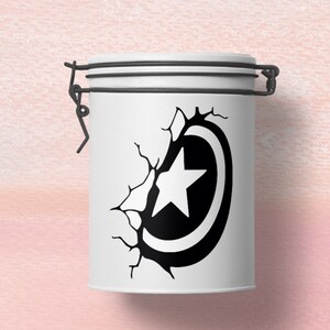May include: A white ceramic jar with a black and white graphic of a star inside a circle, appearing to break through a cracked wall. The jar has a metal lid with a latch.