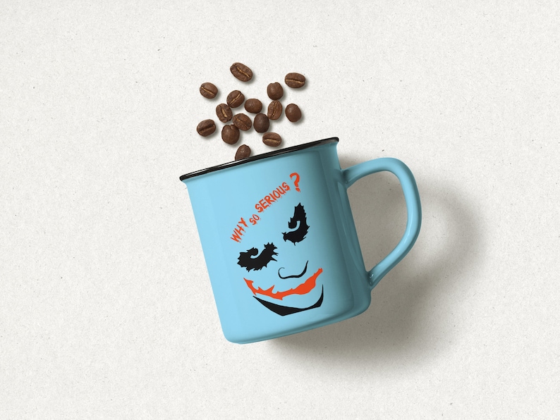 May include: A light blue mug with a black rim and handle. The mug has a black and orange Joker face with the text "WHY SO SERIOUS?" printed on it. Coffee beans are scattered around the mug.