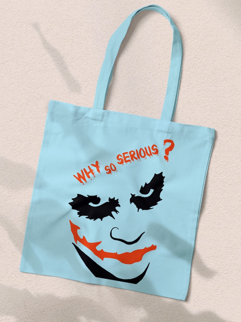 May include: Light blue canvas tote bag with a black and orange Joker face graphic and the text "WHY SO SERIOUS?" in red.