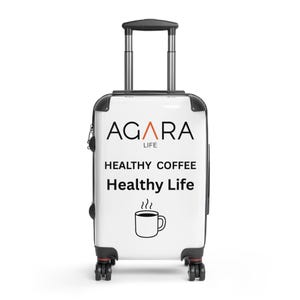 May include: A white travel suitcase with black trim and a retractable handle. The suitcase has the text "AGARA LIFE" in black and orange, along with "HEALTHY COFFEE Healthy Life" and a coffee cup graphic.