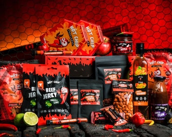May include: A collection of Hot Chip brand products, including jerky, chips, sauces, and syrup. The packaging is predominantly red and black, with chili pepper graphics and text. Various flavors are displayed, such as chili apple, mango, and plum. Fresh limes, apples, and chili peppers are also present.